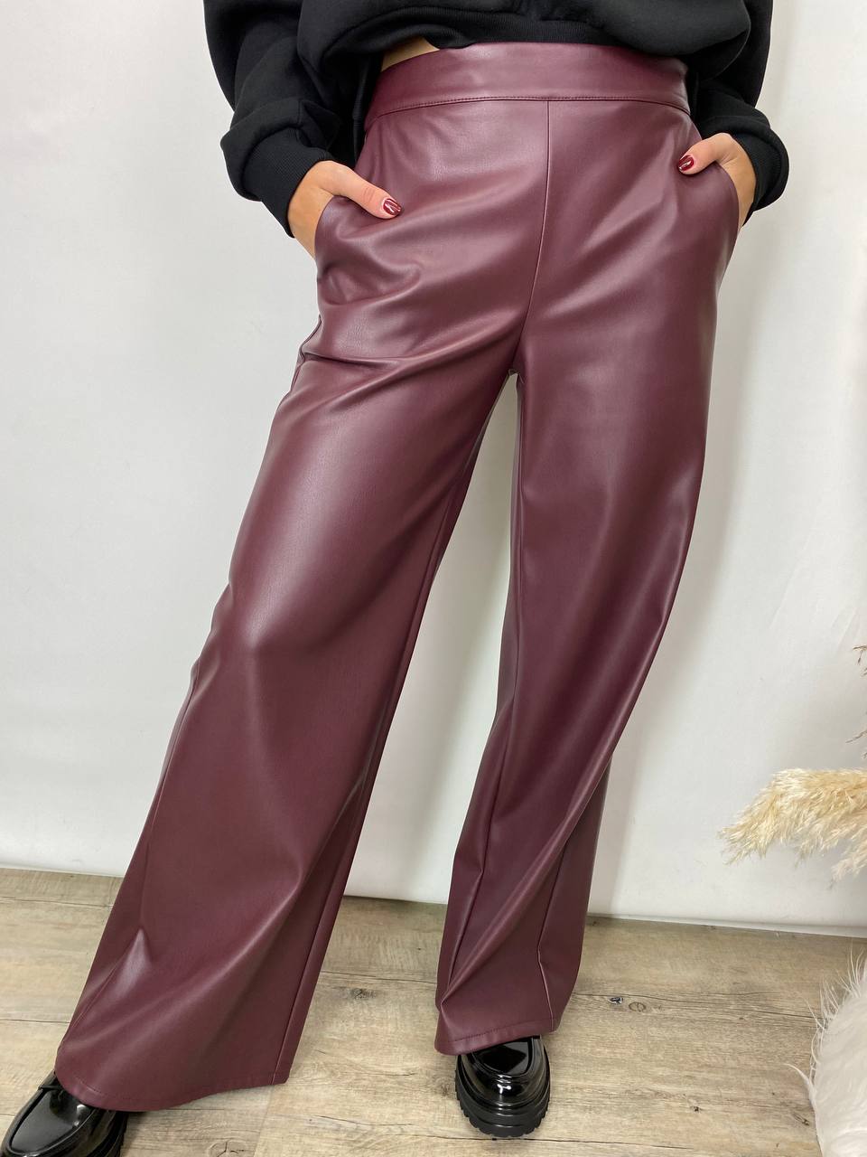 "Pantalone palazzo in ecopelle opaca color vinaccia con tasche applicate e chiusura laterale a zip."